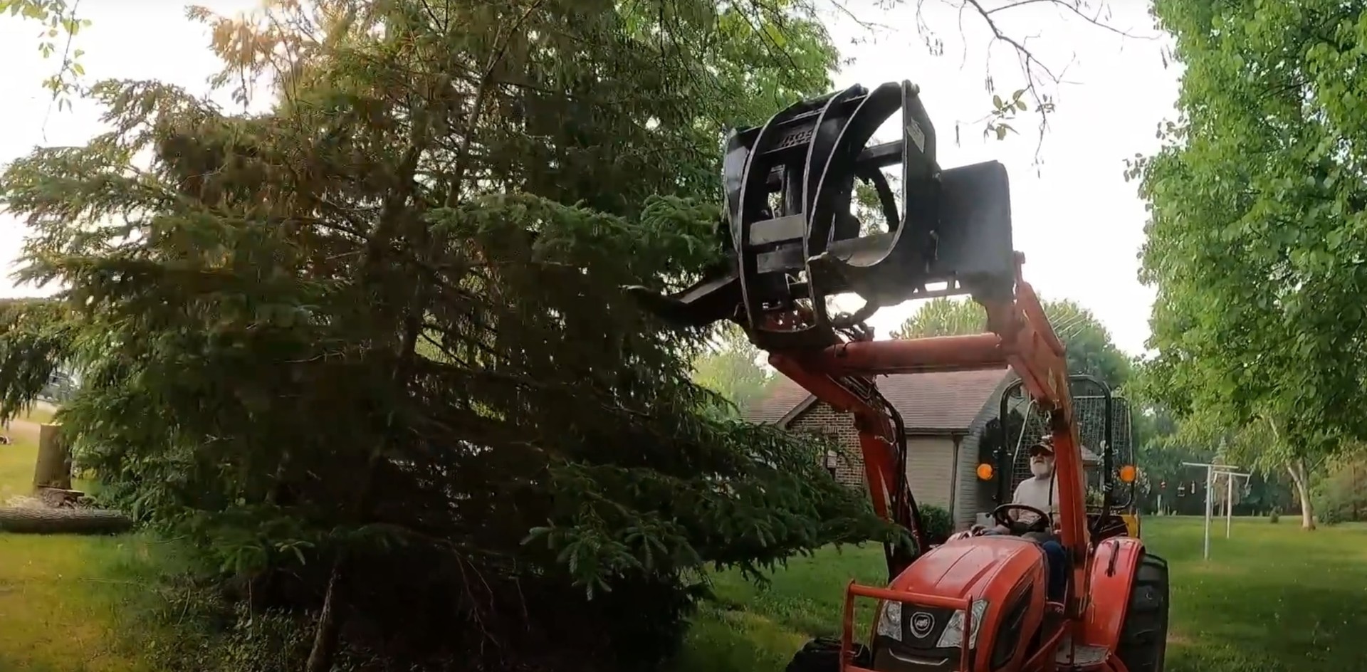 Professional tree removal with crane and heavy equipment Heavy machinery performing tree removal near residential property